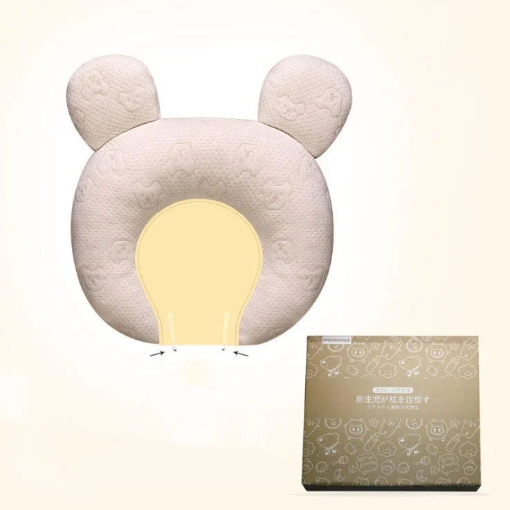 Soft beige bear-shaped baby pillow with ear details, textured fabric, and matching box.
