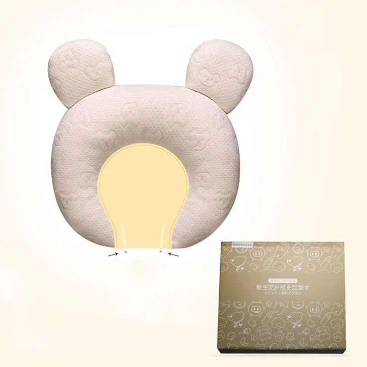 Soft beige bear-shaped baby pillow with ear details, textured fabric, and matching box.