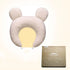 Soft beige bear-shaped baby pillow with ear details, textured fabric, and matching box.