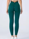 Emerald green high-waisted leggings with ruched back, stretchy fit, paired with white sneakers