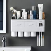 Modern wall-mounted white bathroom organizer with cups, toothbrushes, toiletries and drawers.