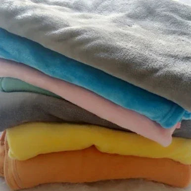 Stack of soft fleece blankets in gray, blue, pink, yellow, and orange colors