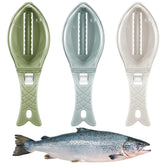 Three plastic fish-shaped fish scalers in green, blue, and white above a fresh fish.