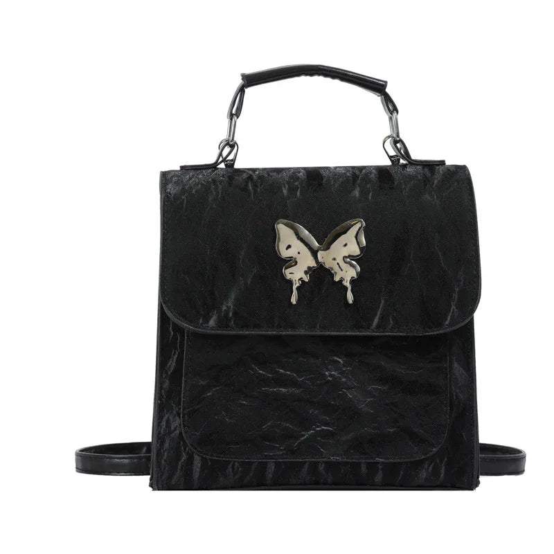 Black faux leather backpack with metallic butterfly accent, structured fit, top handle and shoulder straps