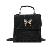 Black faux leather backpack with metallic butterfly accent, structured fit, top handle and shoulder straps