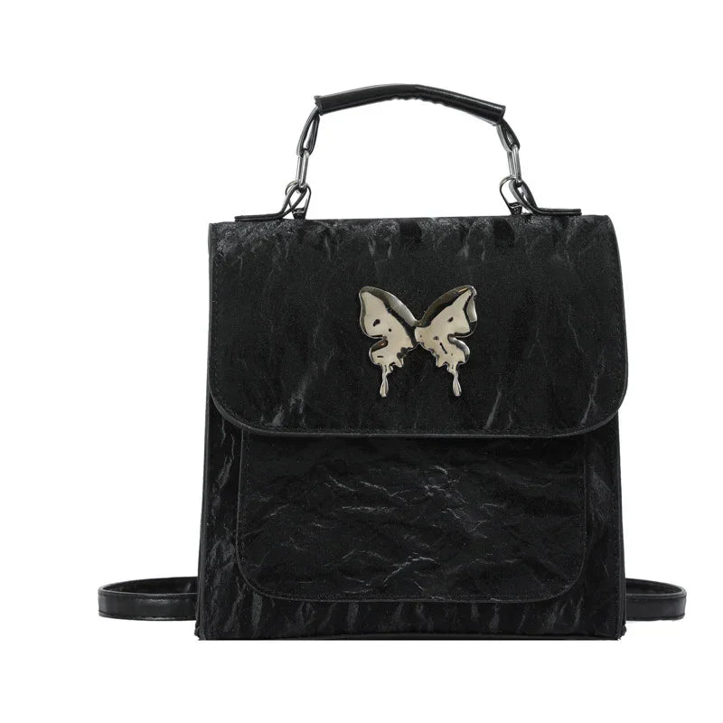 Black faux leather backpack with metallic butterfly accent, structured fit, top handle and shoulder straps