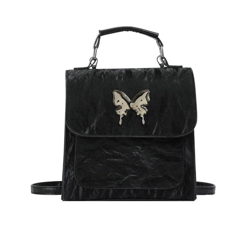 Black faux leather backpack with metallic butterfly accent, structured fit, top handle and shoulder straps