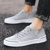 Light gray suede low-top sneakers with white chunky soles, worn with black cuffed jeans