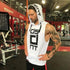 Man wearing white sleeveless hoodie with bold graphic text, relaxed fit, at gym