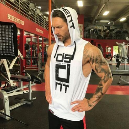 Man wearing white sleeveless hoodie with bold graphic text, relaxed fit, at gym