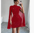 Woman wearing a fitted red glitter mini dress with cape sleeves in a modern room