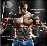 Muscular man wearing black EMS muscle stimulators on arms, shoulders, and abs in gym setting