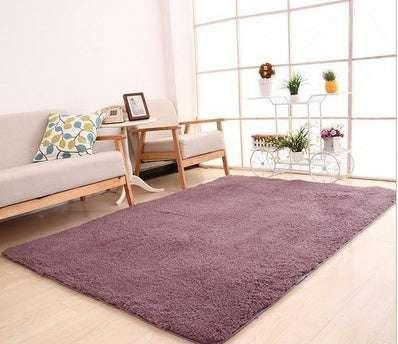Plush purple area rug in a modern living room with wooden floor and neutral sofa