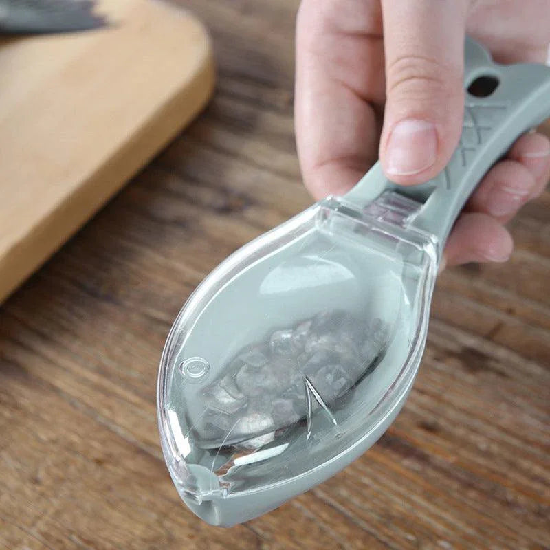 Hand holding a gray plastic fish scaler with a transparent cover for collecting scales
