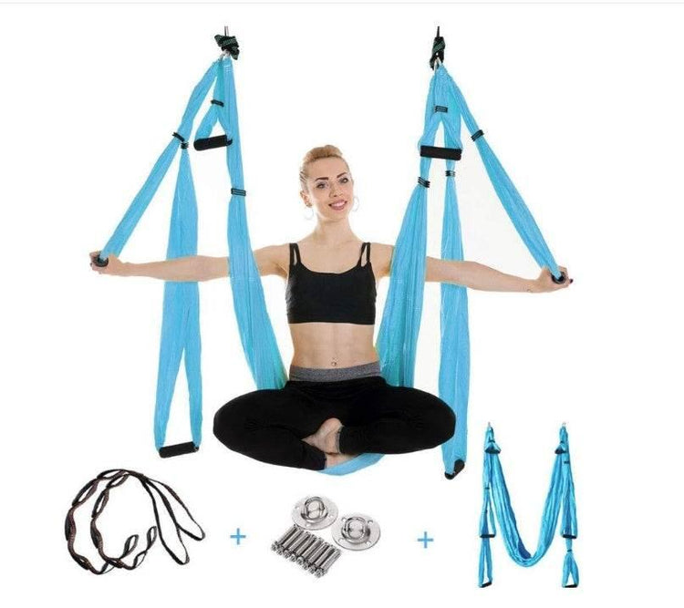 Woman in black sportswear using a blue aerial yoga hammock with installation accessories.