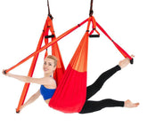 Woman in blue sports bra and black leggings using red aerial yoga swing, performing a split