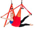 Woman in blue sports bra and black leggings using red aerial yoga swing, performing a split