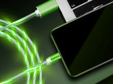 Green LED charging cables connected to a smartphone and laptop on dark background
