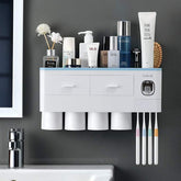 Modern white wall-mounted bathroom organizer with cups, toothbrushes, and toiletries on a grey wall.