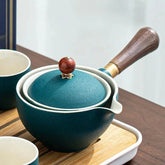 Elegant teal ceramic teapot with wooden handle and ornate lid on wooden tray