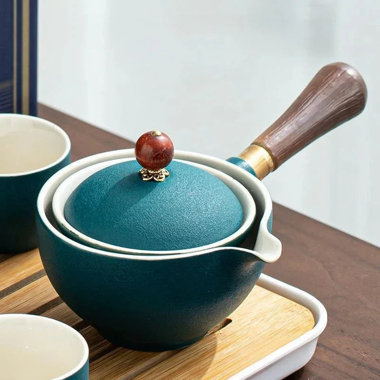 Elegant teal ceramic teapot with wooden handle and ornate lid on wooden tray