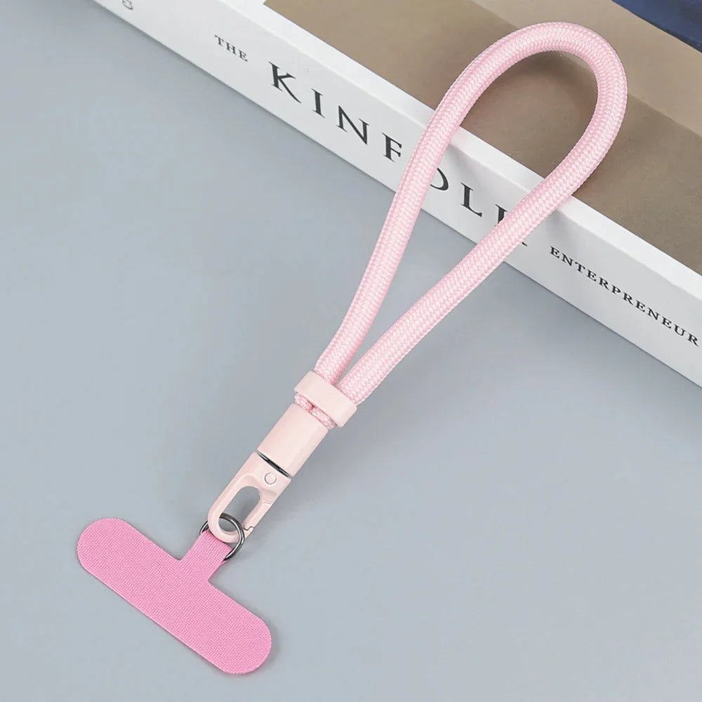 Pink nylon wrist lanyard with metal clasp, minimalist style, tech accessory on gray surface.