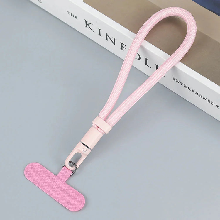 Pink nylon wrist lanyard with metal clasp, minimalist style, tech accessory on gray surface.