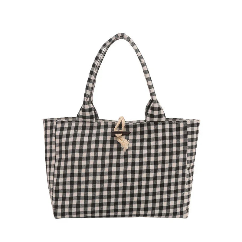 Black and white checkered tote bag with fabric handles and rope button closure.