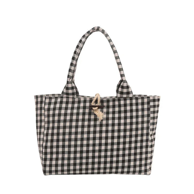 Black and white checkered tote bag with fabric handles and rope button closure.
