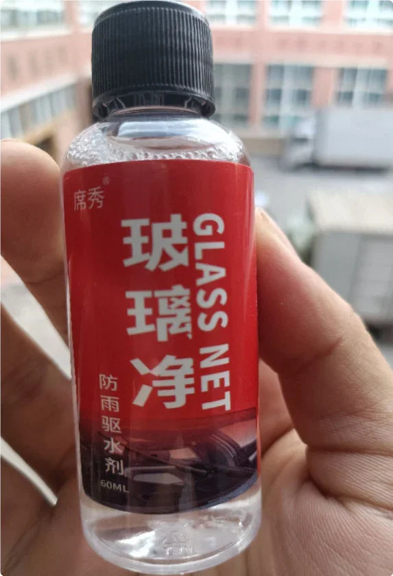 Hand holding a small clear bottle with red label, black cap, featuring white Chinese and English text.