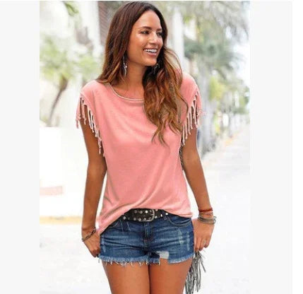 Woman wearing a pink fringed short sleeve top with relaxed fit and blue denim shorts