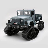 Gray off-road RC truck with large rubber treads and rugged plastic body on white background.