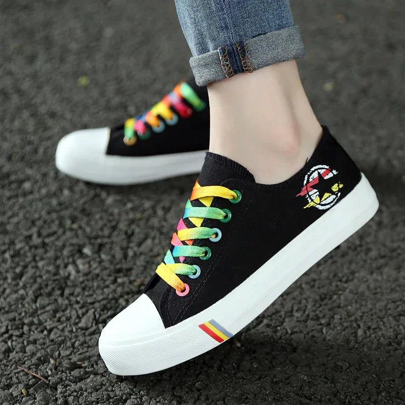 Black canvas sneakers with rainbow laces and white soles, low-top casual fit.