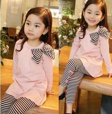 Girl wearing pink long-sleeve tunic with striped bow and matching striped leggings, casual fit