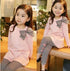 Girl in light pink long-sleeve dress with large striped bow and black and white striped leggings