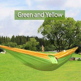 Outdoor green and yellow hammock, lightweight fabric, spacious fit, hanging between trees on grass.
