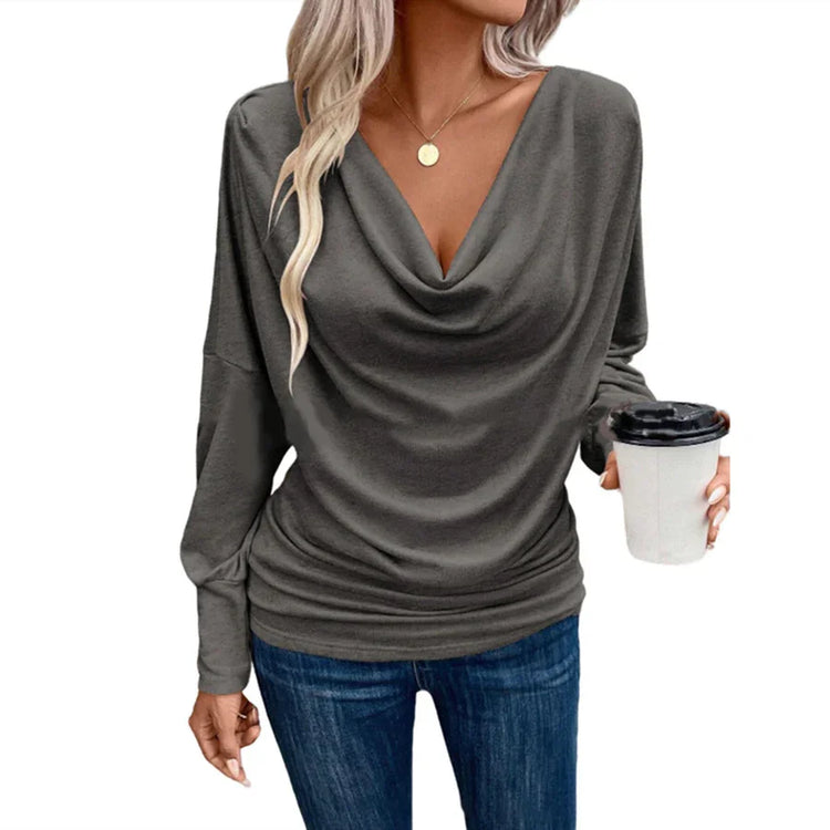 Woman in a loose-fit dark gray cowl neck long sleeve top and blue jeans