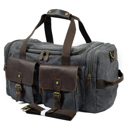 Gray canvas duffel bag with brown leather pockets, multiple zippers, and adjustable strap