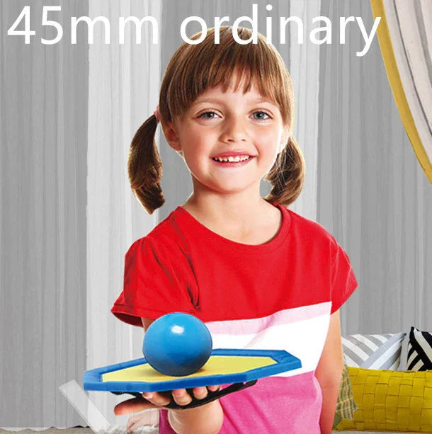 Girl in a red short sleeve colorblock shirt, holding a blue and yellow toy indoors.