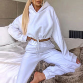 Woman wearing white cropped hoodie and joggers loungewear set, relaxed fit, fleece material.