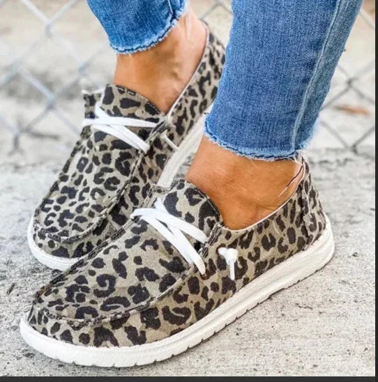 Leopard print canvas slip-on shoes with white soles and laces, paired with blue jeans