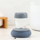 Grey and clear scrubber with textured base, soft plastic material, compact ergonomic fit