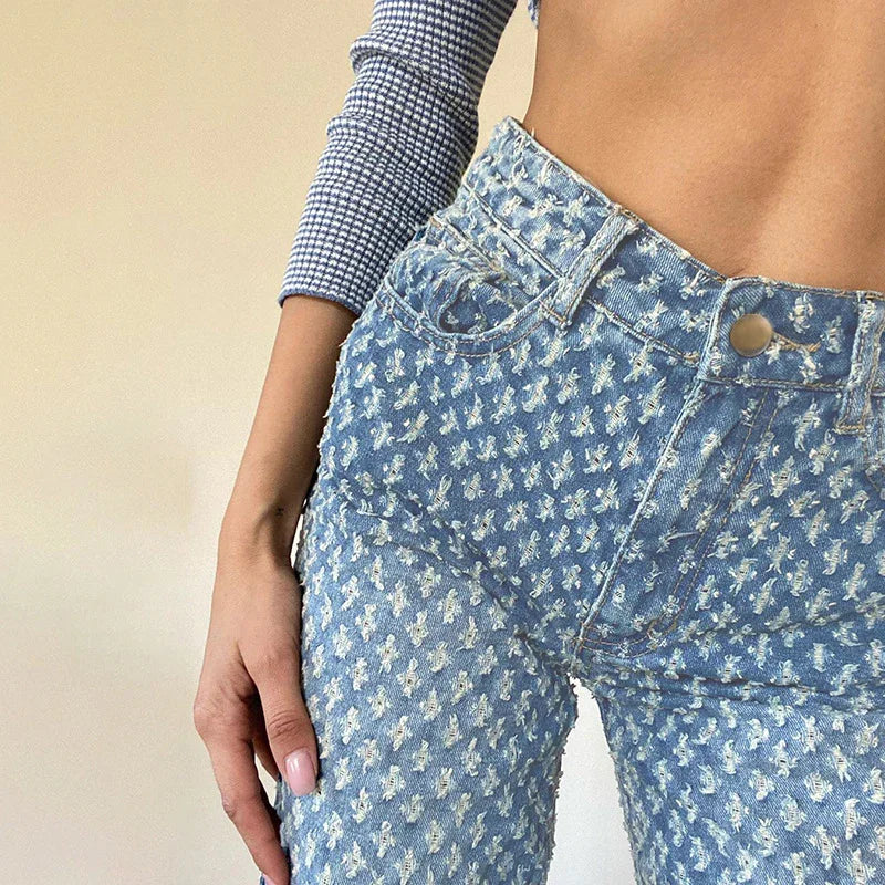 High-waisted blue denim jeans with white floral pattern, slim fit, textured material