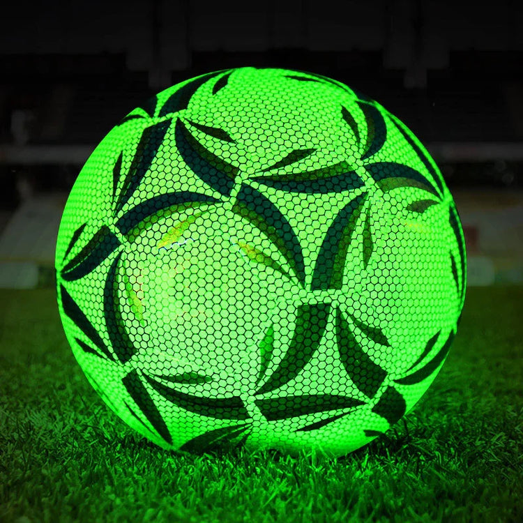 Glowing neon green soccer ball with black geometric patterns on grass at night