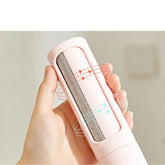 Hand holding a pink lint remover with textured cleaning surface and ergonomic grip