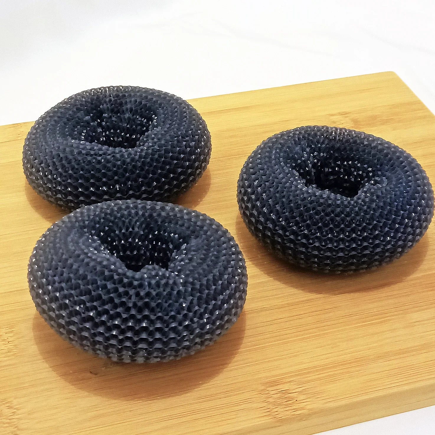 Three black mesh textured rings on a wooden board, modern material and design