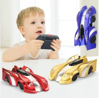 Child playing with remote control, red, gold, and blue plastic race cars on white surface.