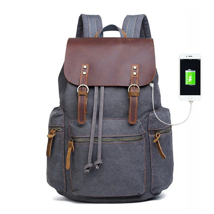 Grey canvas backpack with brown leather flap, multiple pockets, USB charging port, modern fit