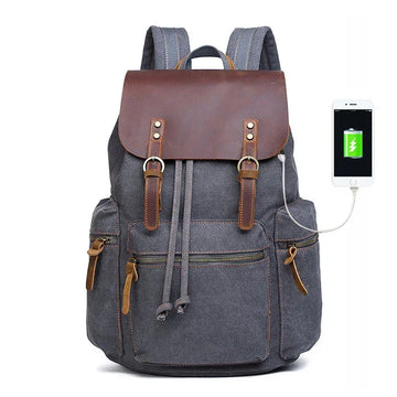 Grey canvas backpack with brown leather flap, multiple pockets, USB charging port, modern fit