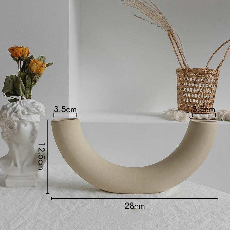 Curved beige ceramic vase with matte finish, minimalist decor on white table, modern style